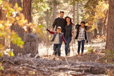 Happy Hispanic family with two children walking in a forest