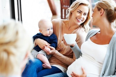 Happy pregnant woman with her friends relaxing at home