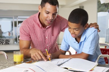 Father Helping Son With Homework In Kitchen