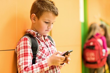 Schoolboy reading a text message on mobile phone.