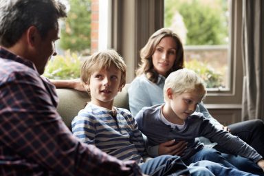 family of four gathered together talking on a couch