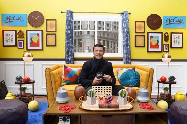 attractive man with dark hair in a styled setting drinking coffee