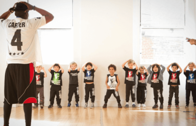 boys mimic a teacher as he puts his hands behind his head in a dance class for boys