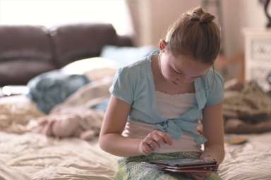 girl-sitting-on-bed-holding-tablet-computer-1313972