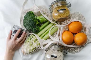 person-holding-green-vegetable-beside-orange-fruit-3737698