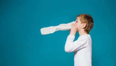 Boy in white clothes blowing his nose