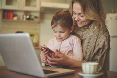 Mother with daughter using mobile phone.