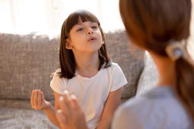 Cute stuttering child girl speaking doing exercises with speech therapist