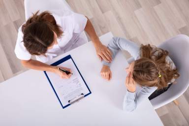 Doctor Sitting With Girl Patient In Clinic