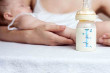 Mother holding a baby and bottle with breast milk