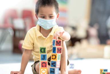 Preschool Boy Wearing A Face Mask In The Classroom Stock Photo