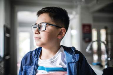 School age boy looking out window