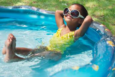 Hispanic girl relaxing in kiddie pool