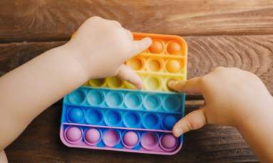 Child hands plays with a push pop fidget toy.