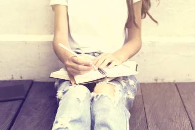 Schoolgirl sitting on floor and wrote in a diary