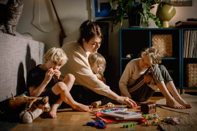 Mother playing with children while sitting on floor at home