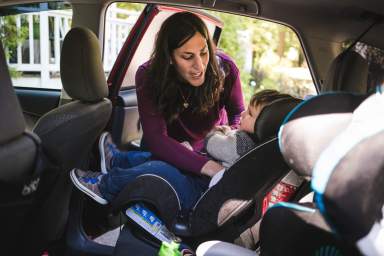 Mother putting son in car seat