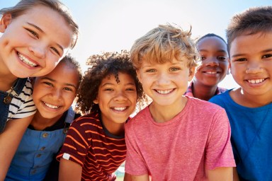 Close up of pre-teen friends in a park smiling to camera