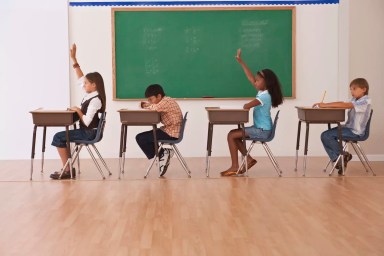 girls raising there hands in classroom