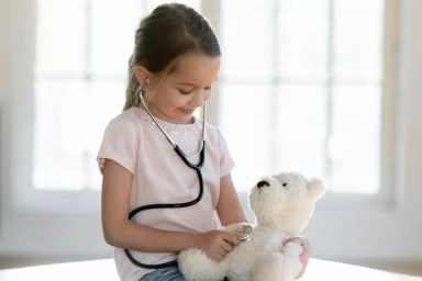 Cute little girl play hospital with teddy bear toy