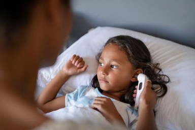 Mother checking daughter temperature with ear thermometer