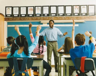 Teacher Standing in Front of a Class of Raised Hands