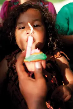 little girl blowing out the candle on her birthday cupcake