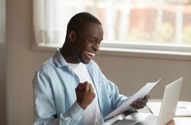 Excited,African,American,Millennial,Male,Worker,Sit,At,Table,Reading