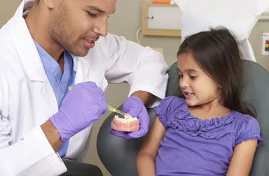 dentist-showing-girl-brushing-teeth