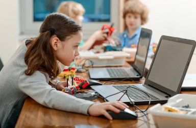 Girl,Using,A,Laptop,While,Assembling,A,Robot,From,Plastic