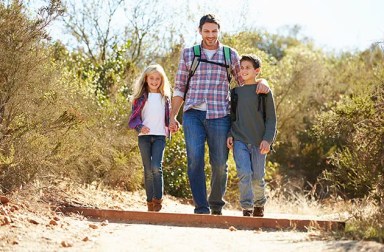 31054011 – father and children hiking in countryside wearing backpacks