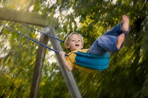 child on swingset; little boy swinging with bare feet