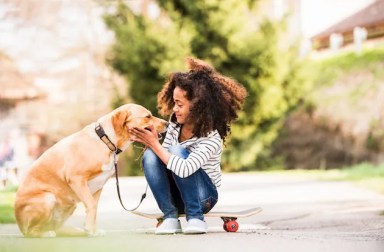 African,American,Girl,Outdoors,On,Skateboard,With,Her,Dog.