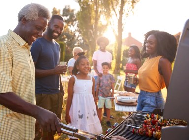 Multi generation black family barbecue, grandad grilling