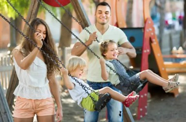 parents-push-children-on-swings-playground