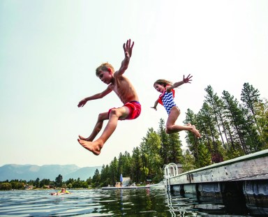 Kids jumping off the dock into a beautiful mountain lake